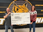 2 individuals are pictured holding a large $1,000 check celebrating a donation made to the school from the community foundation.